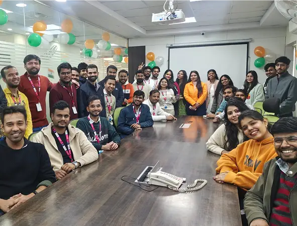 Maxtra Technologies team members gathered around a conference table during an office celebration event