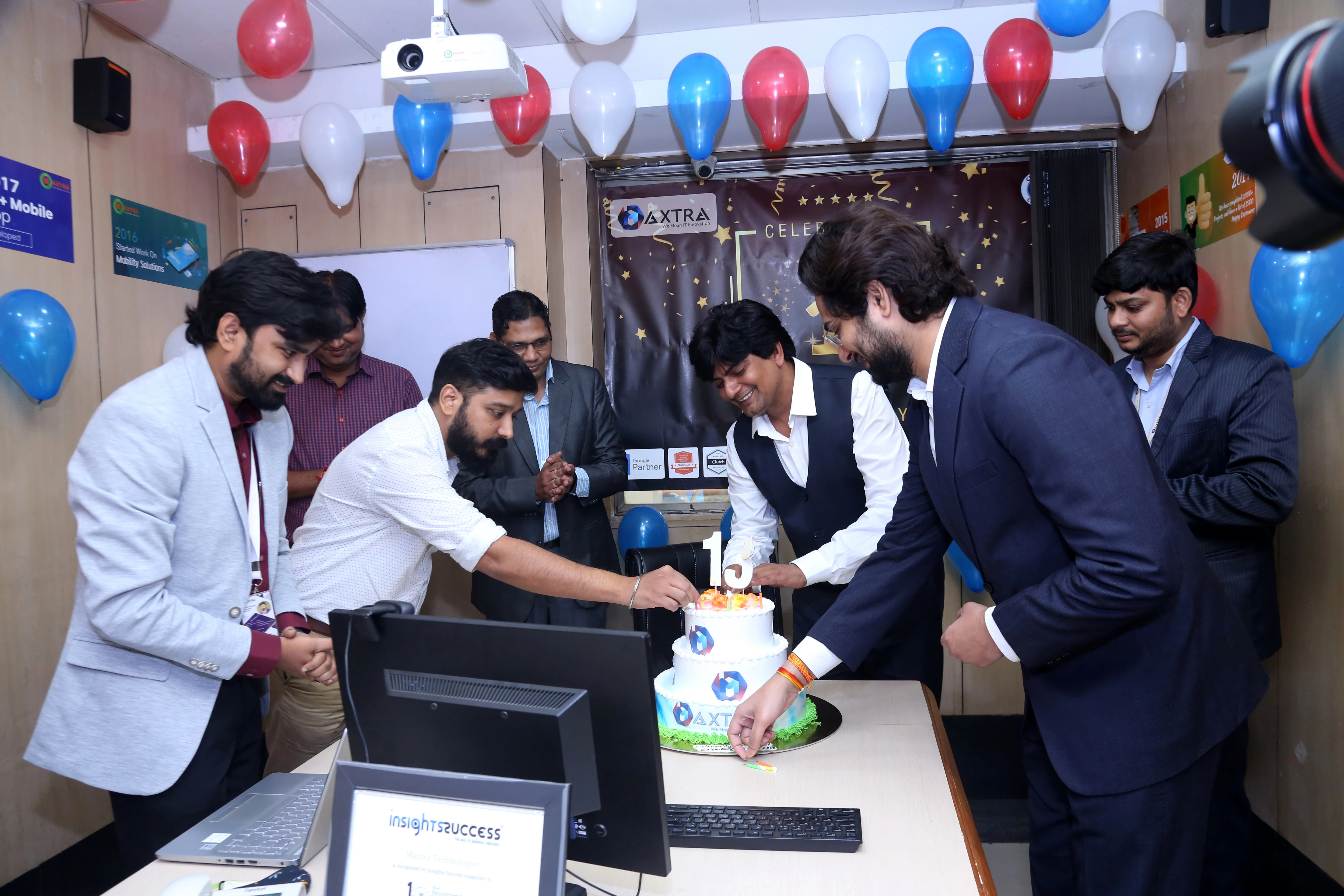 Employees participating in a cake-cutting ceremony during a workplace celebration at Maxtra Technologies